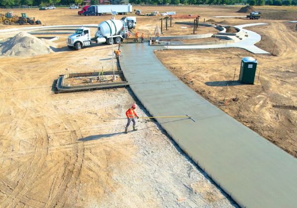 Aerial view of a construction site showing concrete being poured for a new pathway.